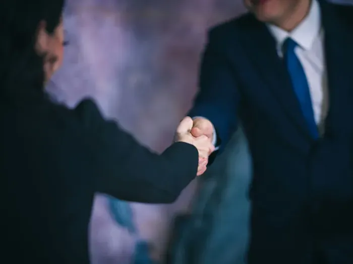 Two professionals in suits shaking hands, symbolizing partnerships and business help found in our directory